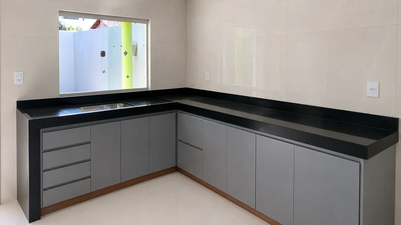 Cozinha em L com bancada de granito preto e rodabanca